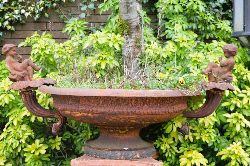 CAST IRON CENTREPIECE PLANTER WITH MOUNTED CHERUBS ON CIRCULAR PLINTH