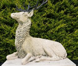 LARGER THAN LIFE SIZE STONE SCULPTURE OF A SEATED STAG