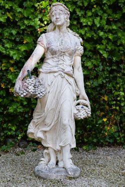 STONE FIGURE OF LADY WITH BASKET OF FRUIT AND FLOWERS