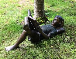 BRONZE GARDEN SCULPTURE OF A RECLINING BOY READING
